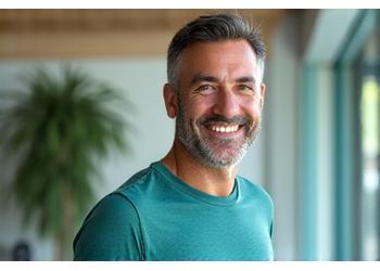 Ritratto professionale di un wellness coach motivante, uomo di età compresa tra 45 e 55 anni, in abbigliamento sportivo, con espressione amichevole.