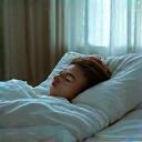 Persona serena che dorme profondamente su un letto confortevole, evidenziando l'importanza dell'ottimizzazione del sonno.
